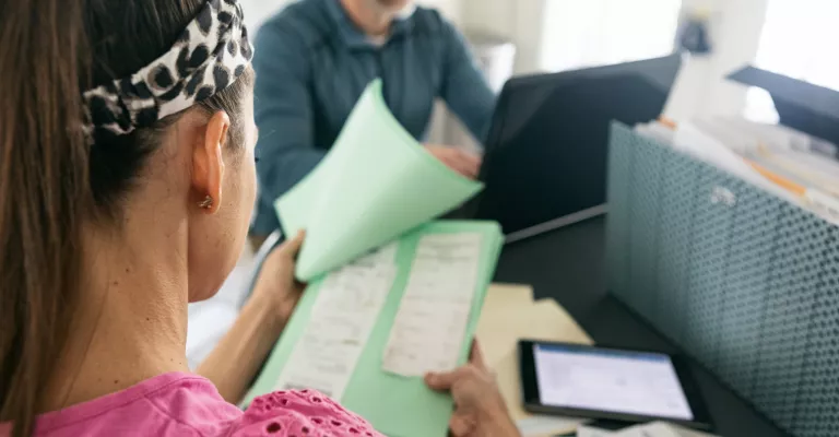 Woman reviewing receipts in front of man on a laptop computer.