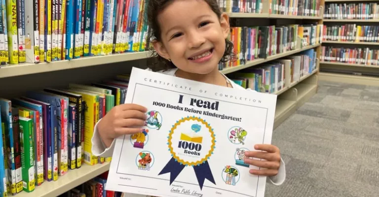 Child holding up a 100 Books Before Kindergarten certificate