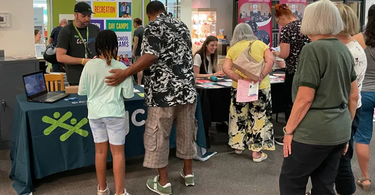 Group of people visiting tables with different club representatives at the Join the Club event