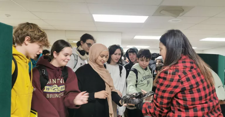 Salthaven staff holding a snake for a group of students to see and touch