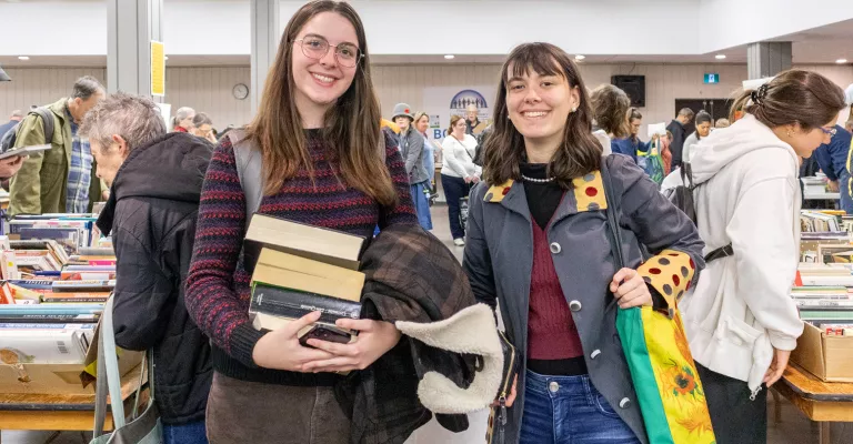 Two people holding books at the fall book sale.