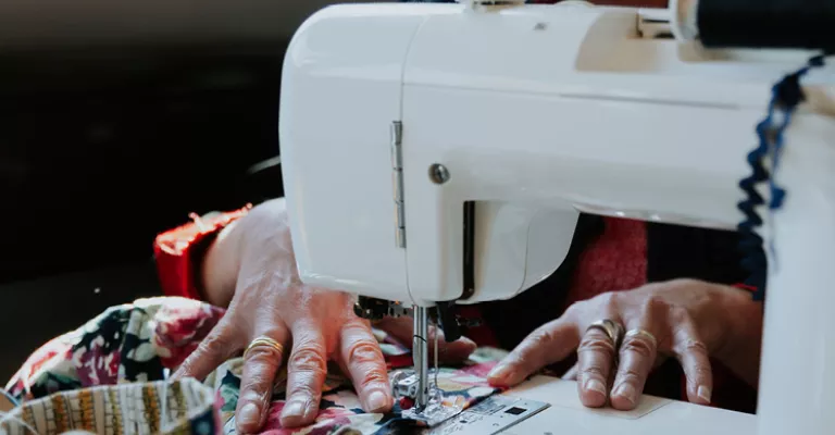 Someone is sitting at a sewing machine mending a garment.