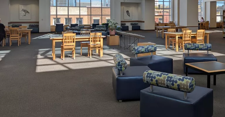 The third floor of central library with seating areas pictures and sun coming through the skylight. 