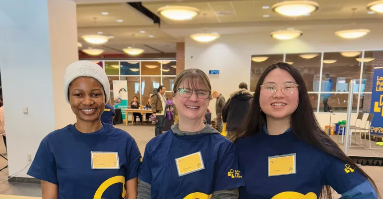 Volunteers smile in matching t shirts and name tags on family literacy day.