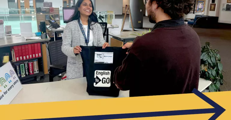 A Library staff member helps a patron with an English to Go employment bag.