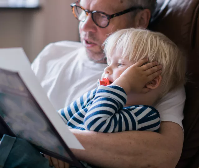 an adult is reading a picture book to a young child 