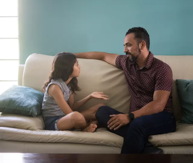 a parent and child having a discussion while sitting on a couch 