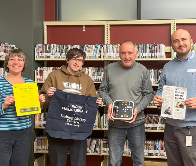 The Visiting Library Services team holding up assistive devices.