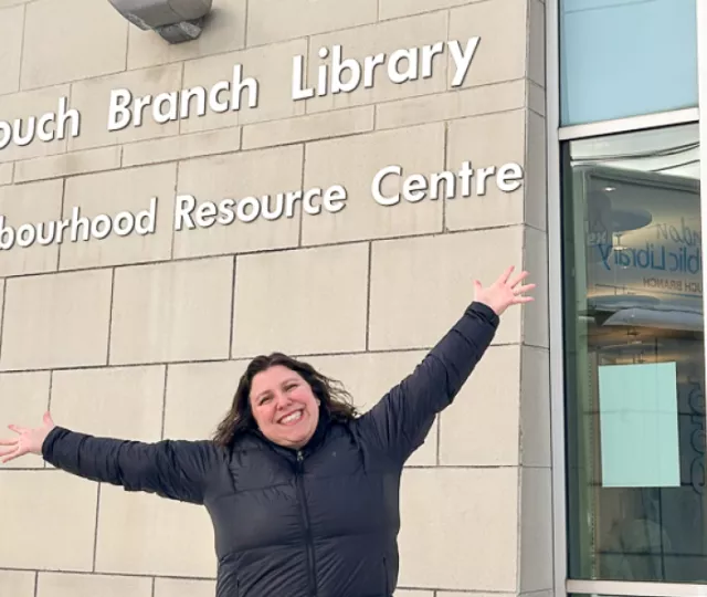 Branch Supervisor Rachel Weisdorf stands proudly in front of Crouch Branch Library's exterior windows.