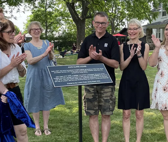 Members of the Historic Sites Committee applaud during a plaque installation ceremony at John Clark House.