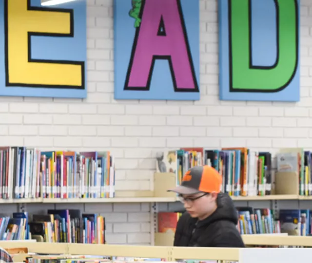 Teens browse the stacks at Byron Library under a sign that says READ.