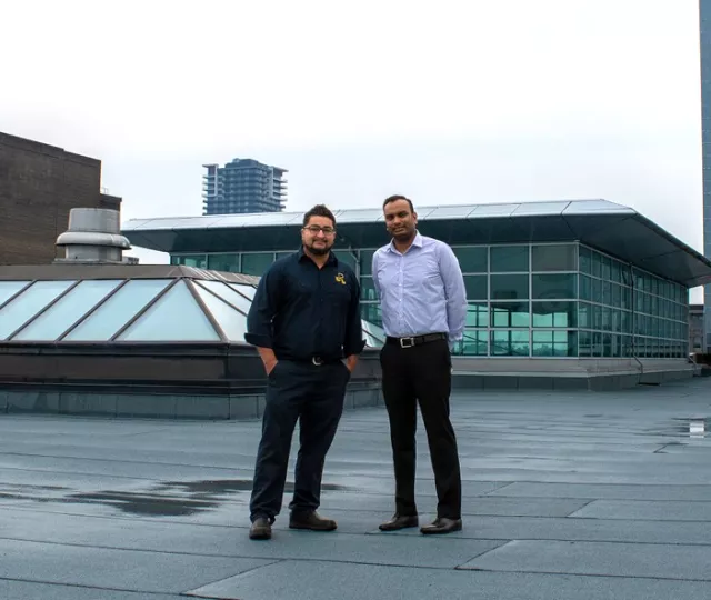 Two Library staff members stand on the repaired roof of Central Library.