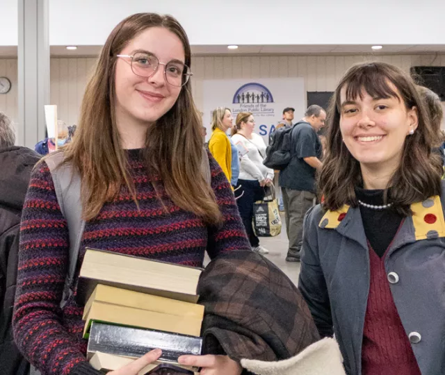 2 young people smile while holding books