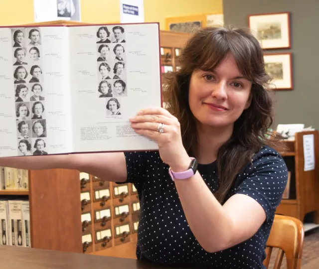 Sammy Orlowski holds up an old yearbook in the London Room at Central Library.