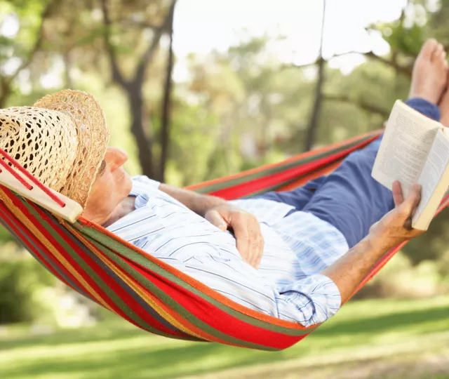 Man Relaxing In Hammock With Book
