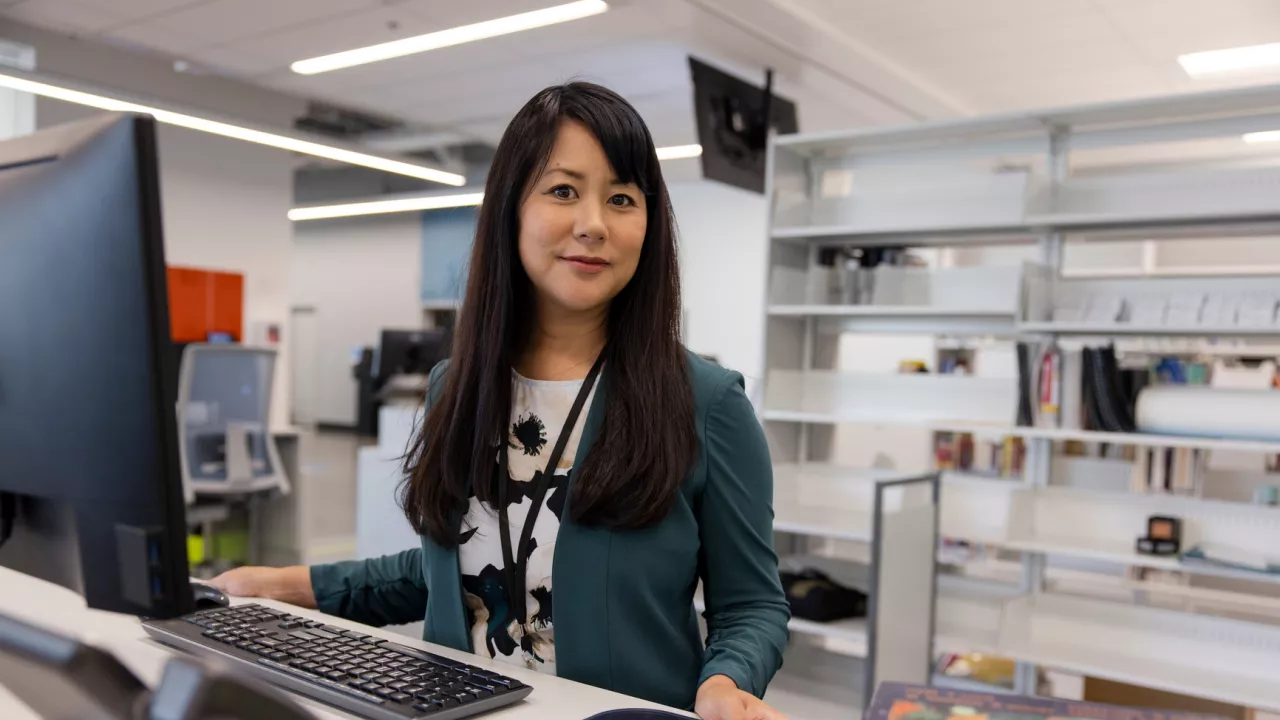 Photo of a female library worker standing at a computer terminal