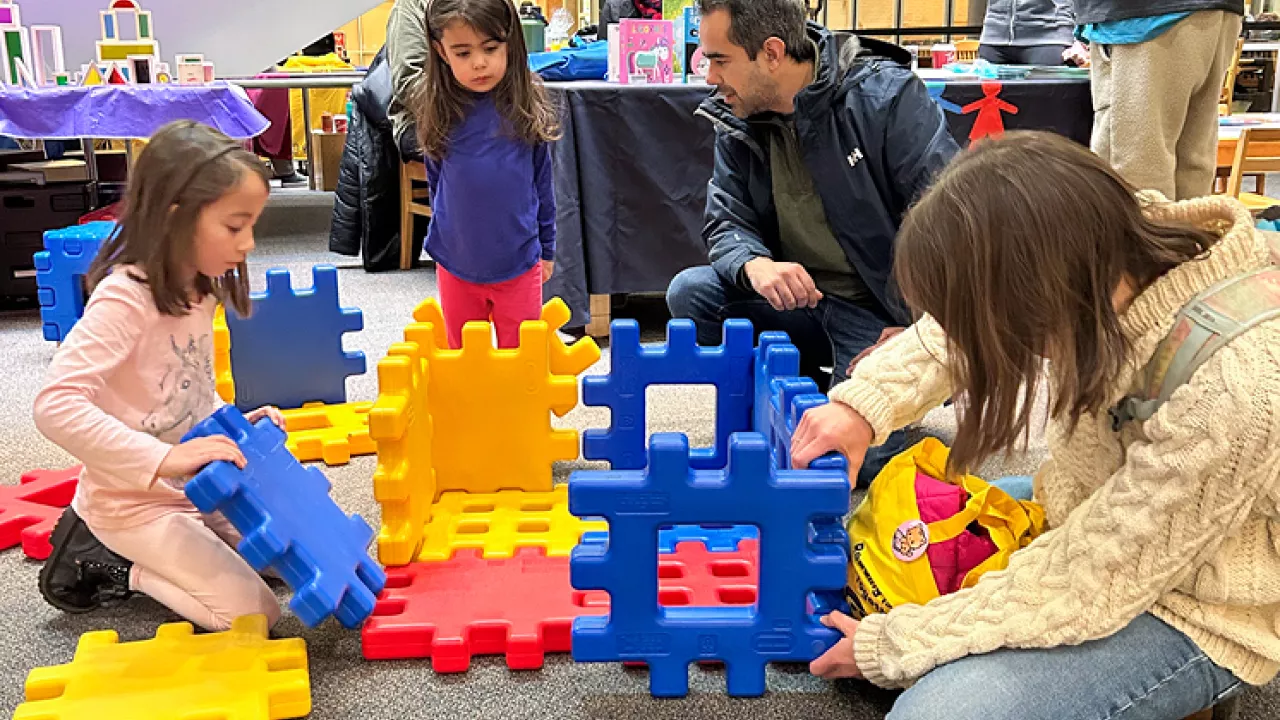 Family on the ground playing with large building blocks
