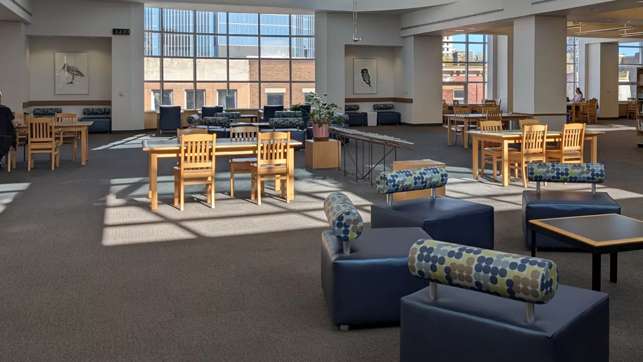 The third floor of central library with seating areas pictures and sun coming through the skylight. 