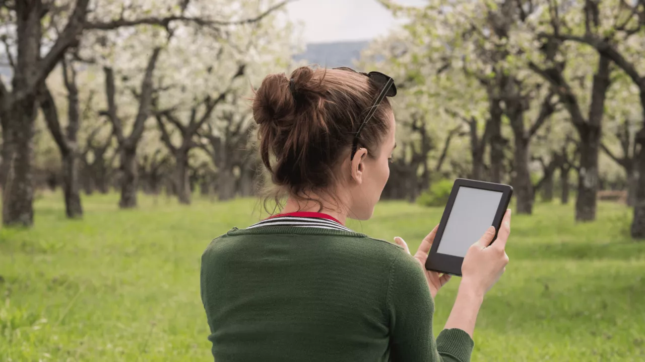 Woman reading on her ereader outside.