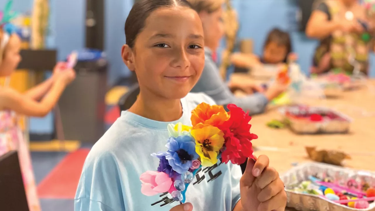 A tween girl holding a flower craft at Central Library