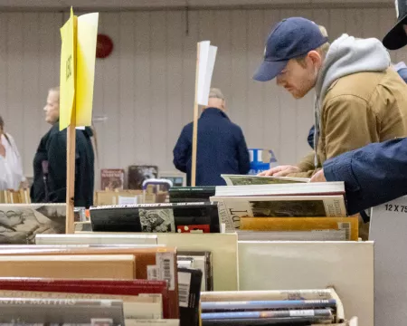Patrons sifting through boxes of books at a sale.