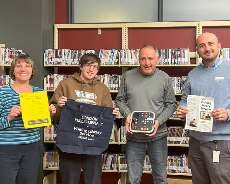 The Visiting Library Services team holding up assistive devices.