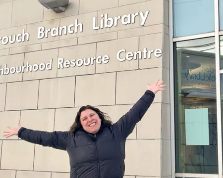 Branch Supervisor Rachel Weisdorf stands proudly in front of Crouch Branch Library's exterior windows.