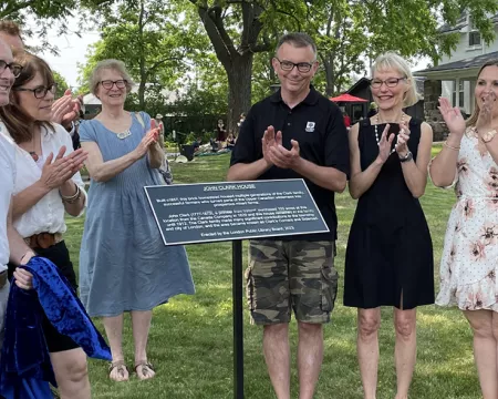 Members of the Historic Sites Committee applaud during a plaque installation ceremony at John Clark House.