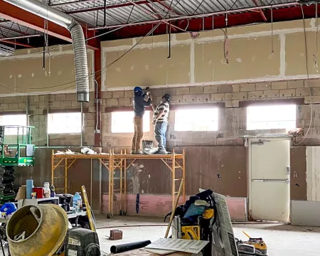 Four construction workers on scaffolding installing windows in a Library renovation.