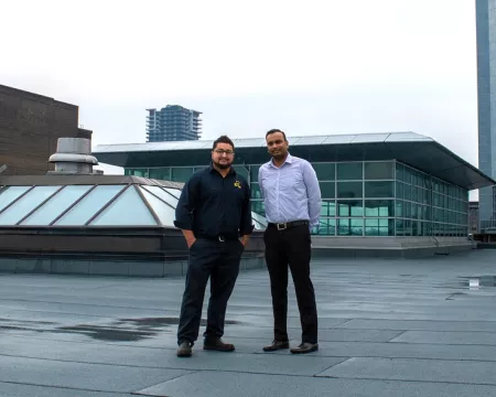 Two Library staff members stand on the repaired roof of Central Library.