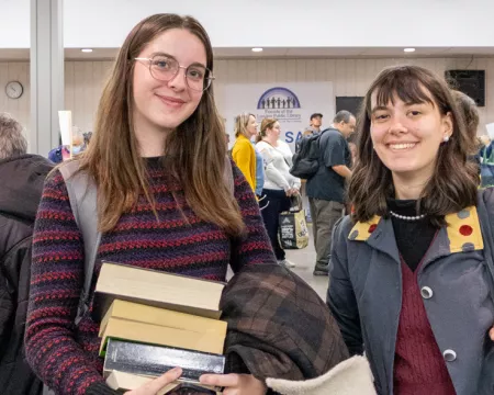 2 young people smile while holding books