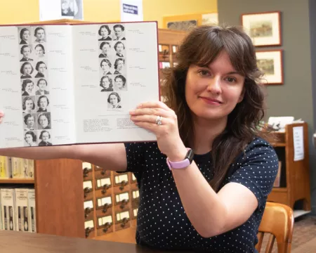 Sammy Orlowski holds up an old yearbook in the London Room at Central Library.