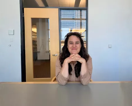 Writer In Residence Anna Chatterton smiles and leans forward on a table.