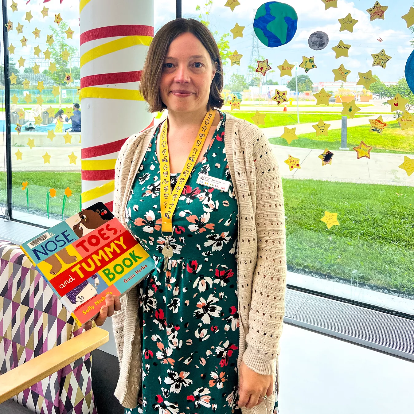Librarian Sara Clarke holding a children's book in the window of Bostwick Branch Library.