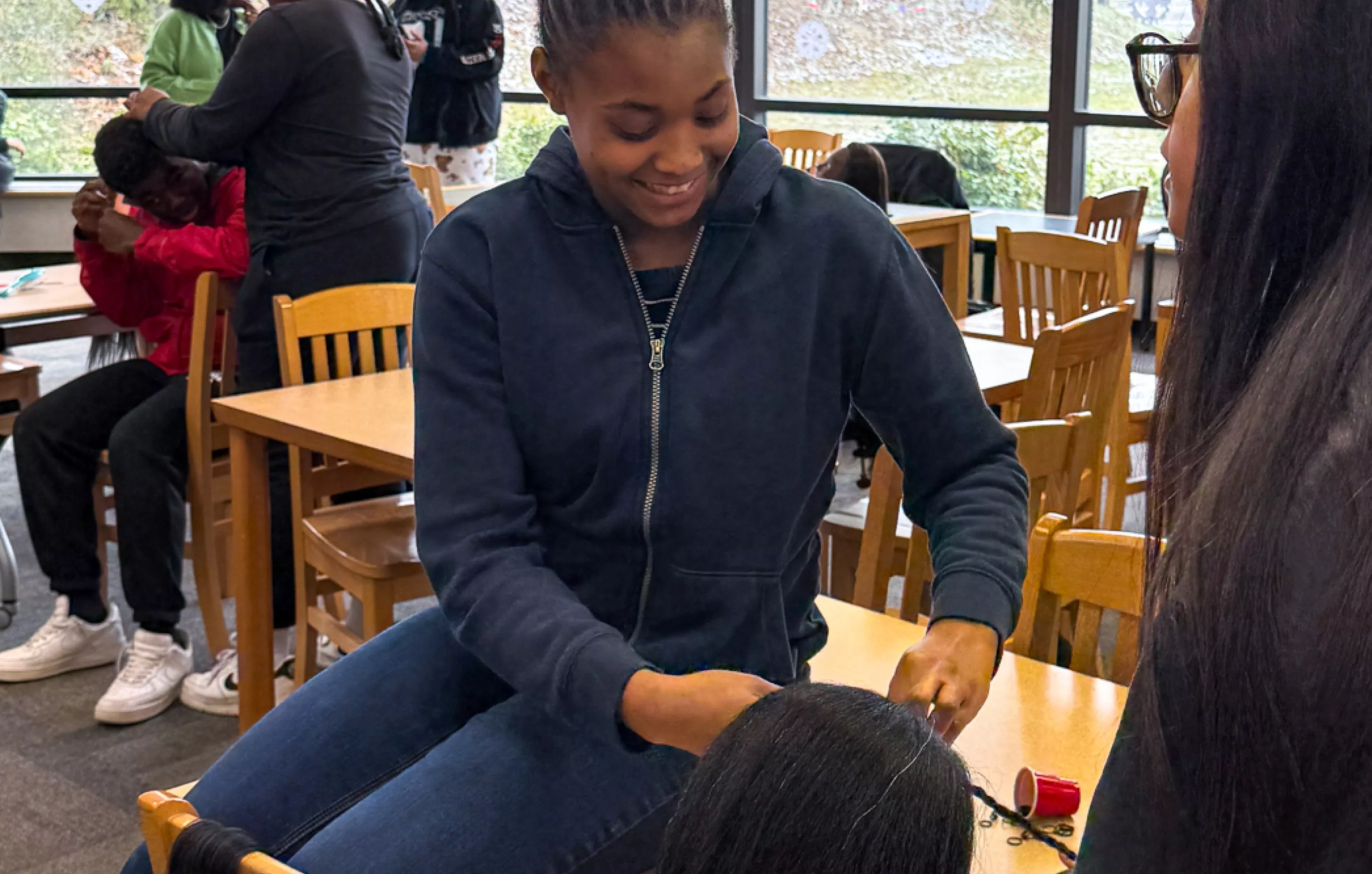 A student practices a braiding technique on a mannequin at the Library.
