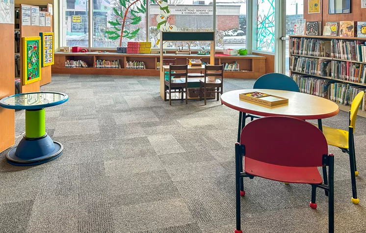 The children's area at Crouch Branch Library is brightly lit by a large window and filled with books and toys, making it a welcoming space for young readers.