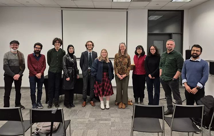 Ten local writers stand in a line at the front of a Library meeting room, with Writer in Residence Seed Teebi
