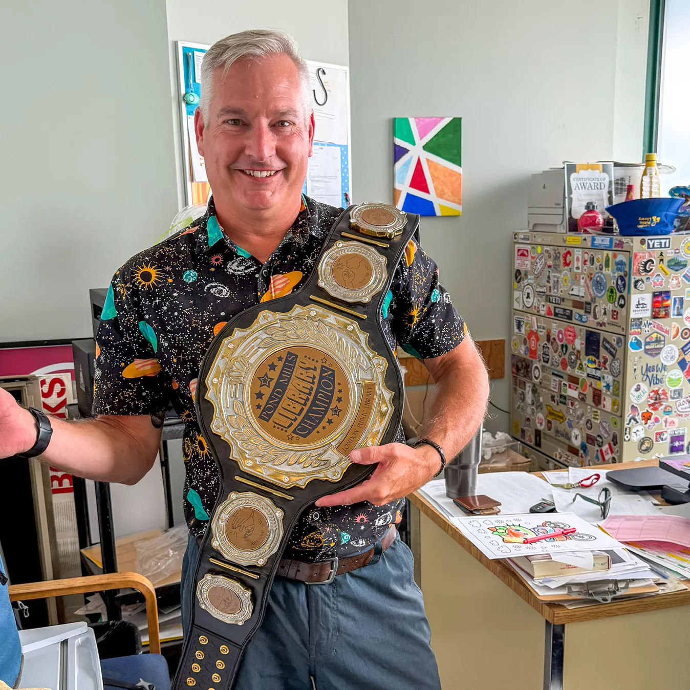 Kevin Moore stands in his office, holding up the championship belt.