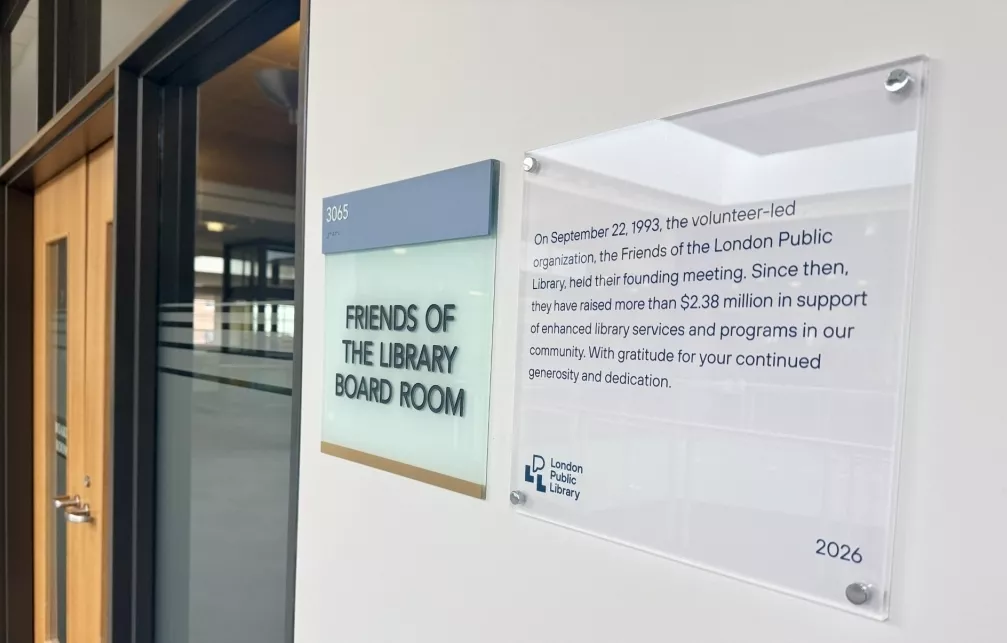 A white plaque on the wall beside the Friends of the Library Board Room reads: On September 22, 1993, the volunteer-led organization, the Friends of the London Public Library, held their founding meeting. Since then, they have raised more than $2.38 million in support of enhanced library services and progams in our community. With gratitude for your continued generosity and dedication. 2026