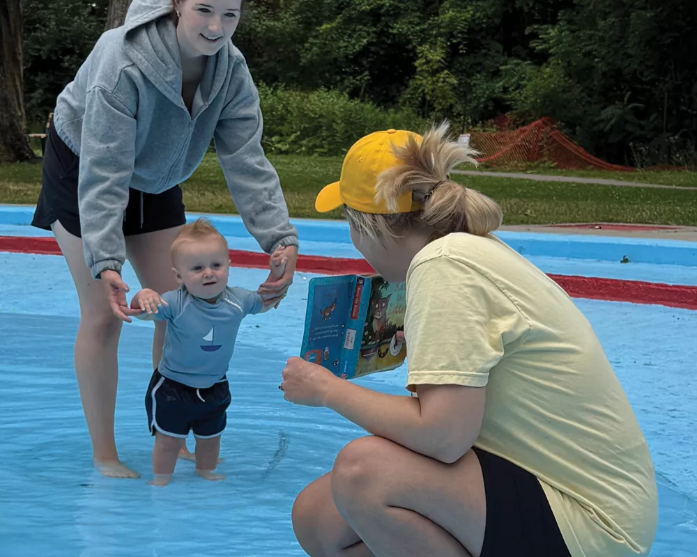 a librarian at an outdoor Water Babies session with a toddler and mom